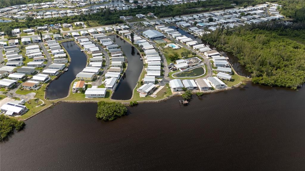 An aerial view shows a mobile home community situated along canals and a large body of water — 4300 RIVERSIDE DRIVE UNIT 114, PUNTA GORDA, FL