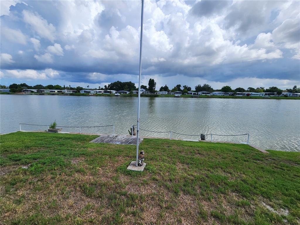 A grassy lawn overlooks a lake with a flagpole and a small dock — 808 53RD AVENUE E UNIT 169, BRADENTON, FL