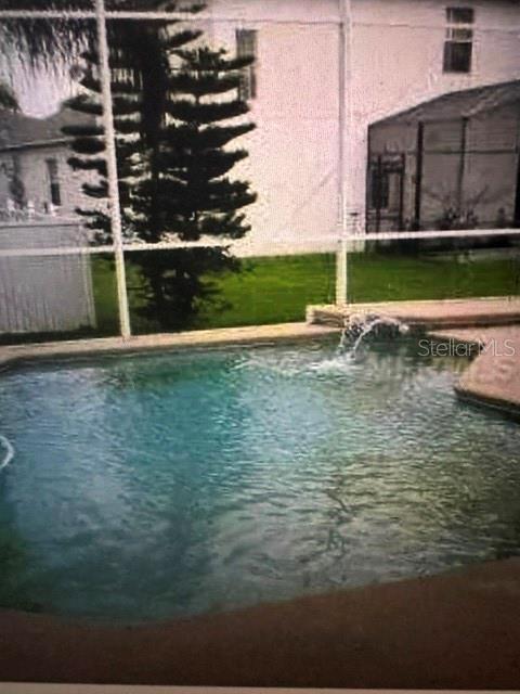 A swimming pool with a water feature is enclosed by a screen in a backyard — 2158 WINTERMERE POINTE DRIVE, WINTER GARDEN, FL