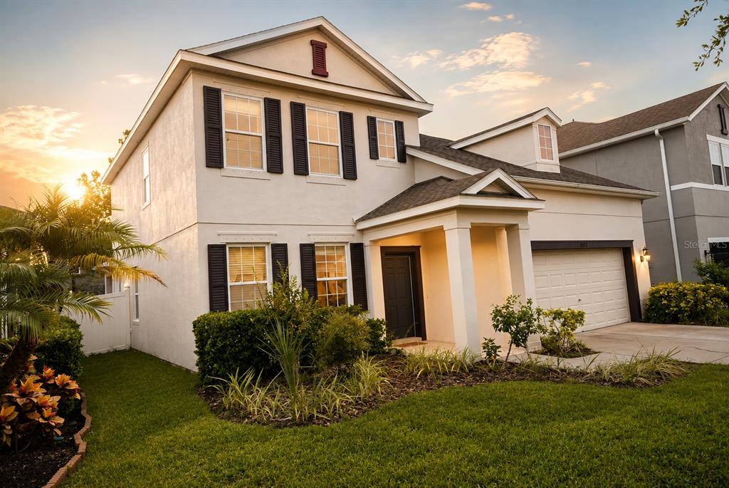 A two-story house with a beige stucco exterior, black shutters, and a front-facing garage — 11543 TANGLE BRANCH LANE, GIBSONTON, FL
