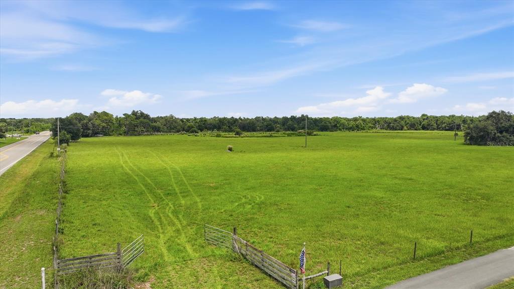 An aerial view shows a large, grassy, fenced-in vacant lot next to a paved road — 13805 COUNTY ROAD 675, PARRISH, FL