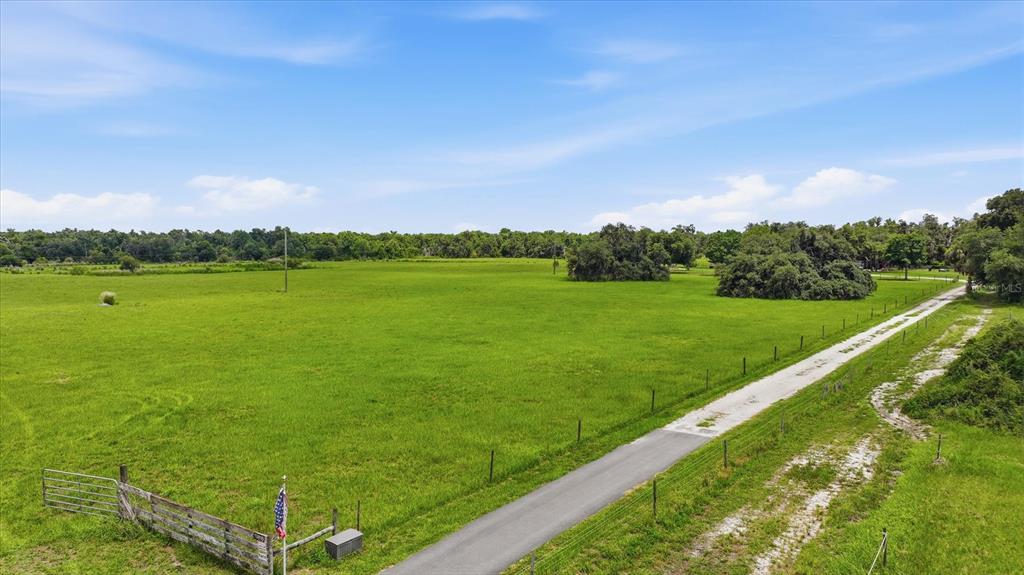 An aerial view shows a large, grassy field bordered by a fence and a paved driveway — 13805 COUNTY ROAD 675, PARRISH, FL