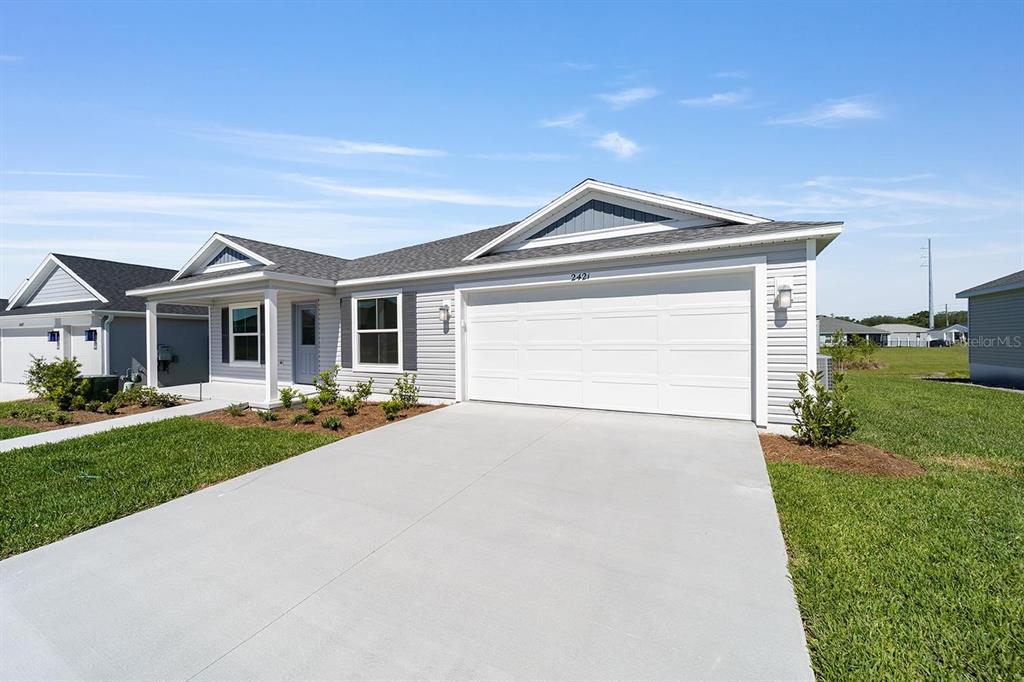 A single-story house with light gray siding, a white garage door, and a concrete driveway — 2421 HOBKIRK LOOP, MIDDLETON, FL