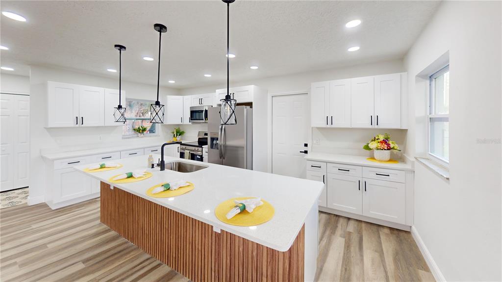 A modern kitchen features white cabinets, a wood-slatted island, and stainless steel appliances — 501 HERITAGE BOULEVARD, WINTER PARK, FL