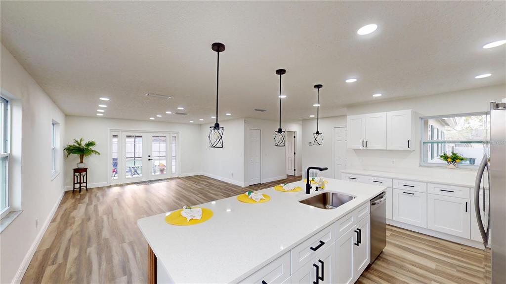 A modern kitchen with white cabinets and a large island overlooks an open living area — 501 HERITAGE BOULEVARD, WINTER PARK, FL