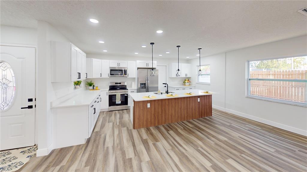 A modern kitchen features white cabinets, a wood-slatted island, and light wood-look flooring — 501 HERITAGE BOULEVARD, WINTER PARK, FL