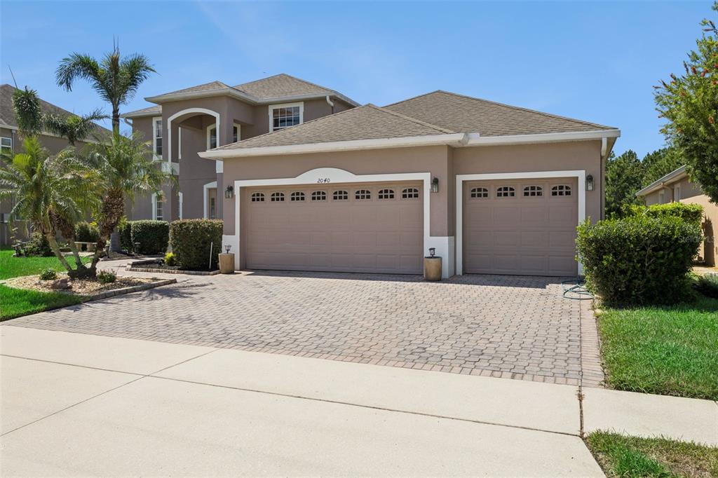 A two-story house with a beige stucco exterior and a three-car paved driveway — 2040 HAWKS LANDING DRIVE, ORLANDO, FL