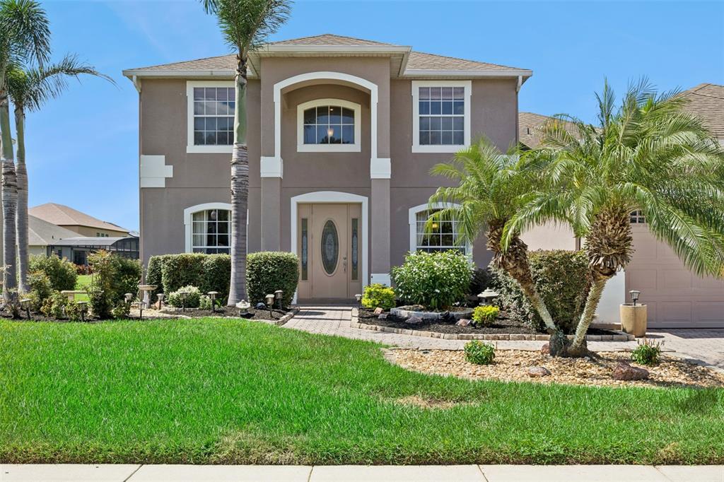 A two-story tan house with a palm tree, a front lawn, and a paved walkway — 2040 HAWKS LANDING DRIVE, ORLANDO, FL