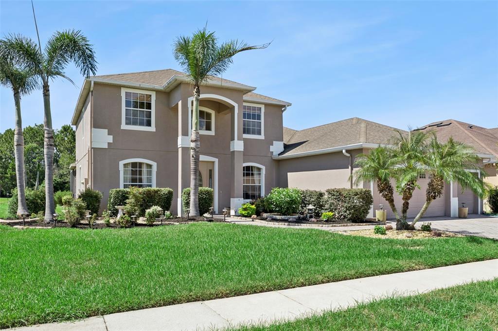 A two-story suburban house with a tan stucco exterior, a shingled roof, and palm trees — 2040 HAWKS LANDING DRIVE, ORLANDO, FL