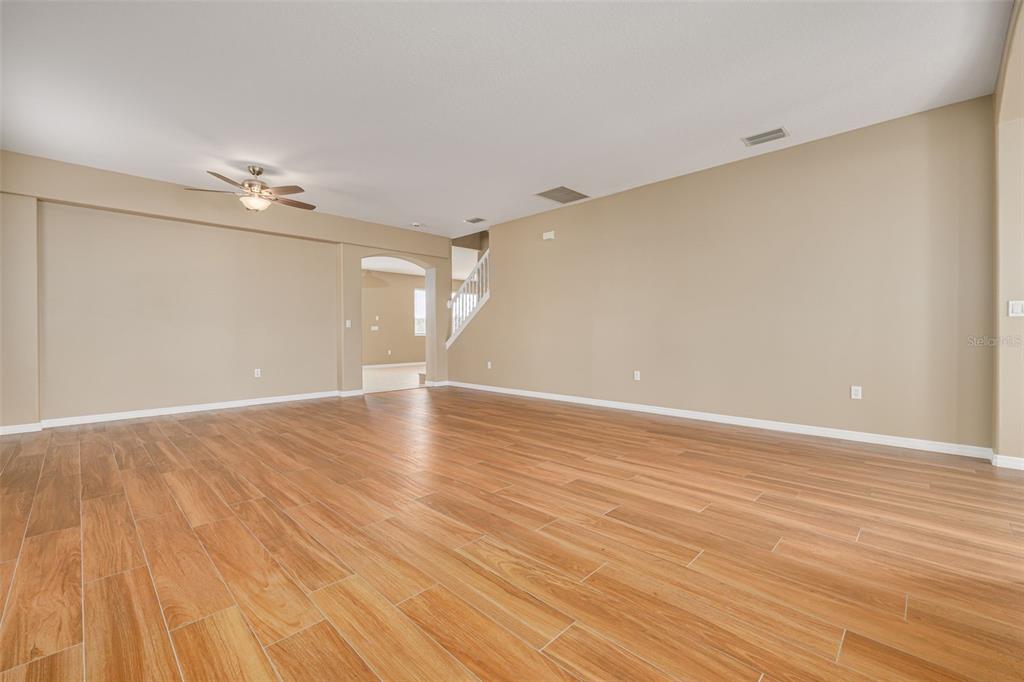 An empty room with light wood-look tile flooring, beige walls, and a ceiling fan — 9028 WILLOWBROOK CIRCLE, BRADENTON, FL