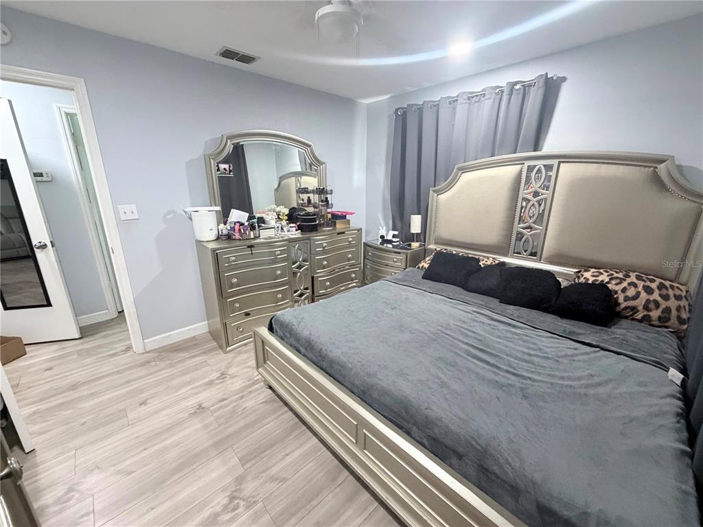 A bedroom features a metallic-finish bed frame, matching dresser with mirror, and light wood flooring — 7281 SE 120TH STREET, BELLEVIEW, FL