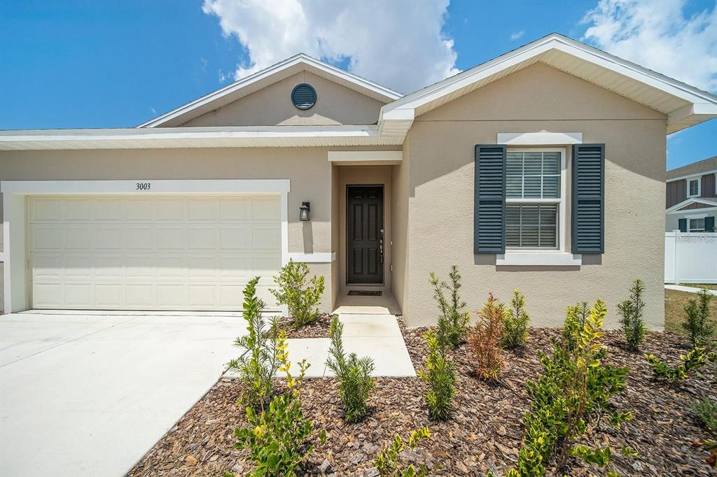 A single-story house exterior features a beige stucco facade, a garage, and a front entrance — 3003 FIN ROAD, WINTER HAVEN, FL