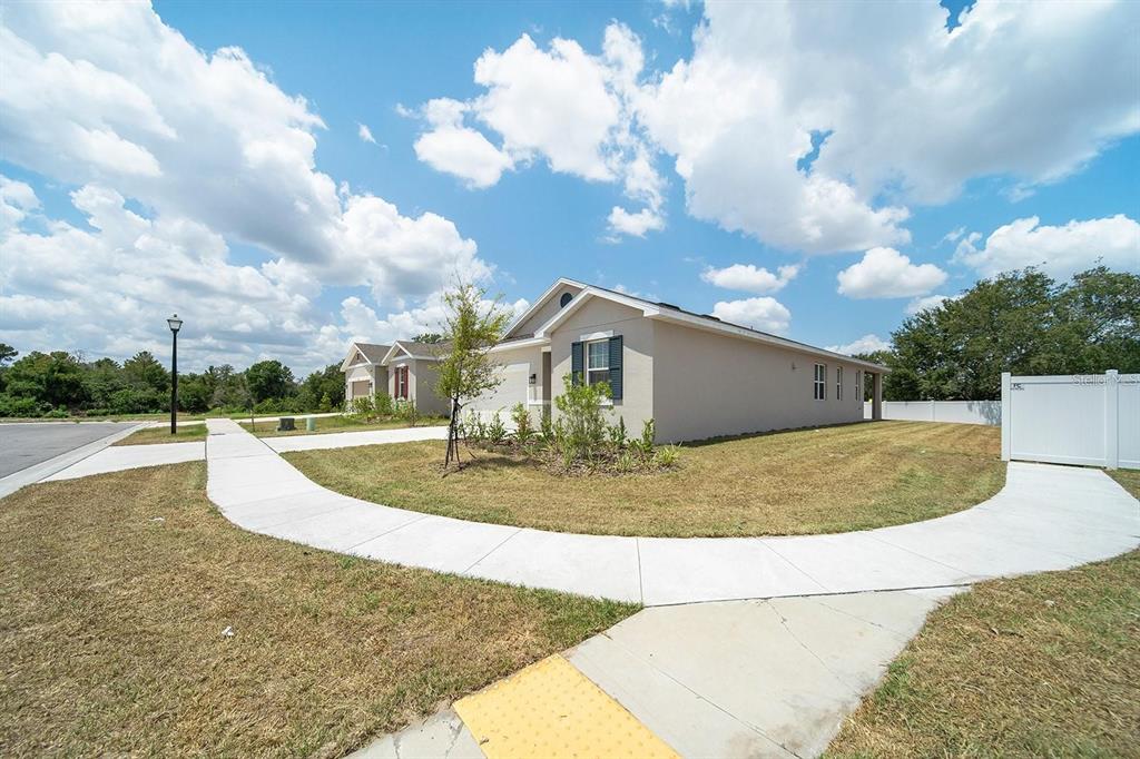 A single-story house with a beige exterior and a sidewalk wrapping around the corner lot — 3003 FIN ROAD, WINTER HAVEN, FL