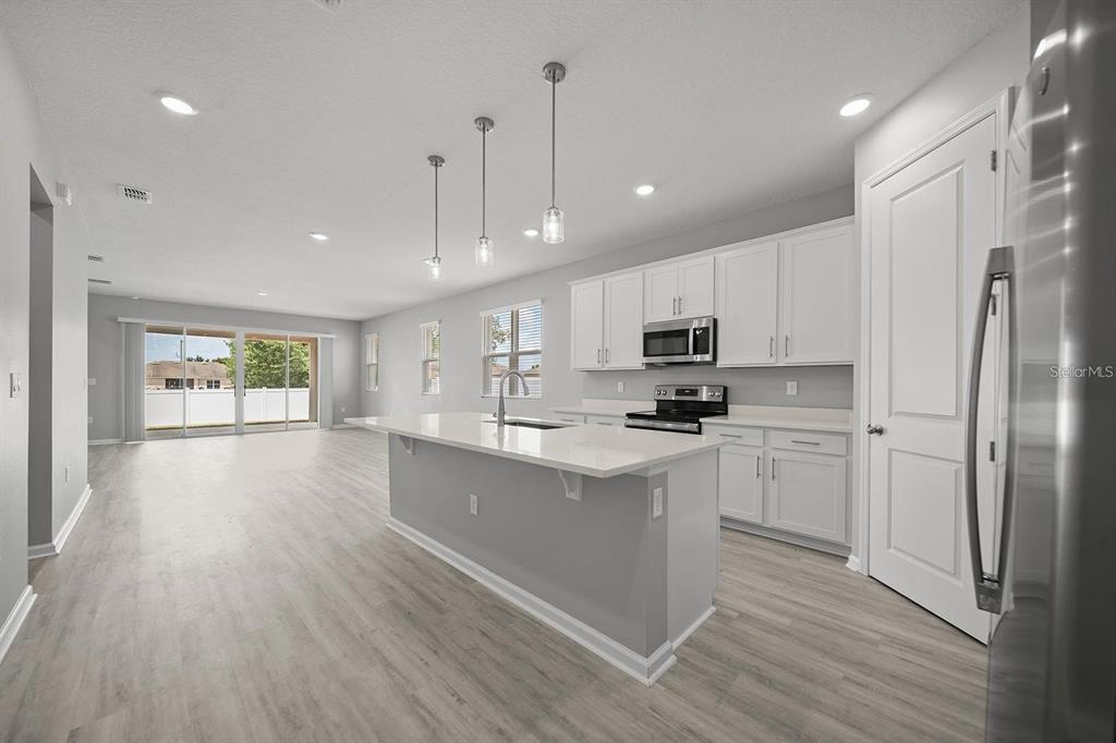 A modern kitchen features white cabinetry, a gray island with a quartz countertop, and light flooring — 3003 FIN ROAD, WINTER HAVEN, FL