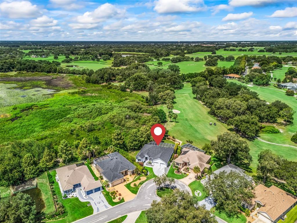An aerial view shows a suburban house with a red location pin on a golf course — 714 CIMARRON AVENUE, THE VILLAGES, FL