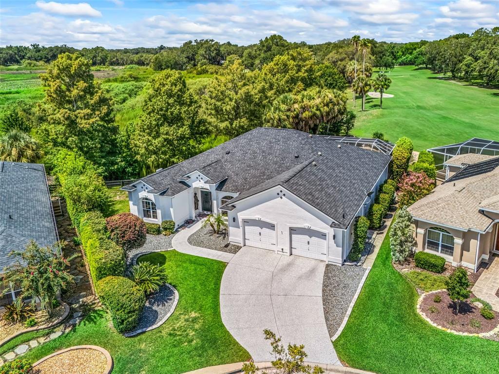 An aerial view shows a white single-story house with a dark roof and two-car garage — 714 CIMARRON AVENUE, THE VILLAGES, FL