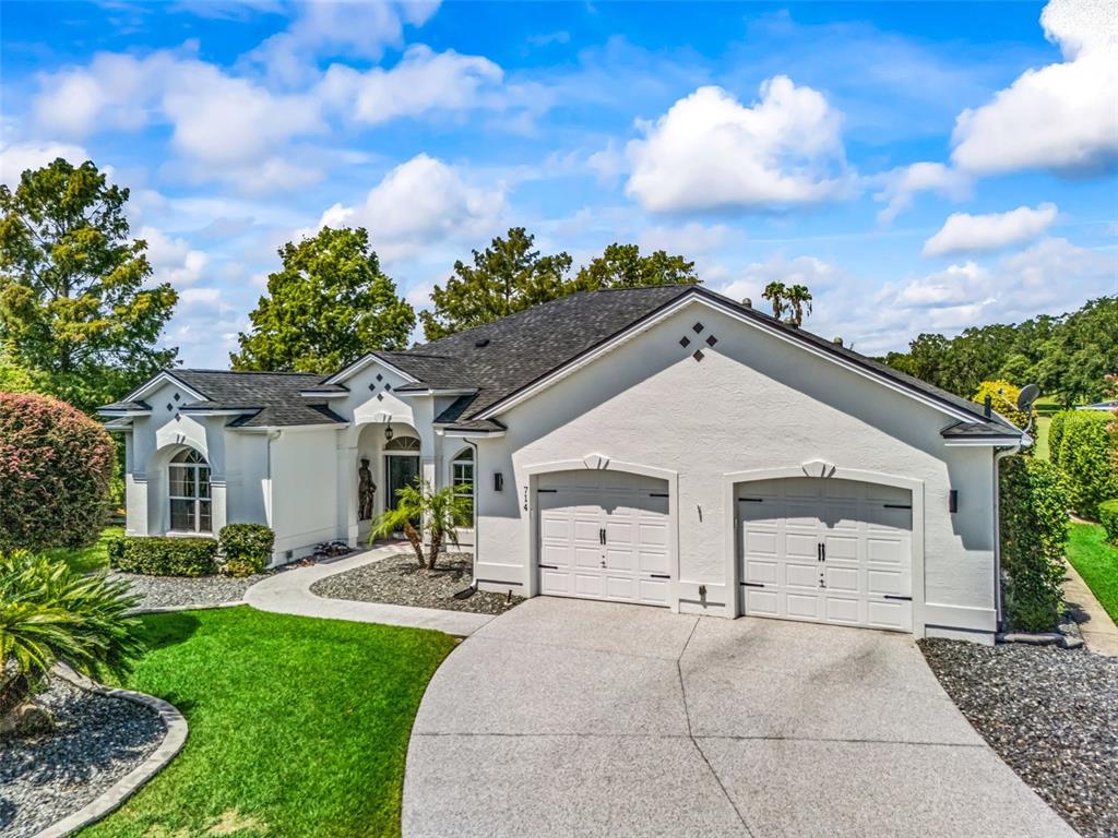 A white stucco house with a two-car garage and a landscaped front yard — 714 CIMARRON AVENUE, THE VILLAGES, FL