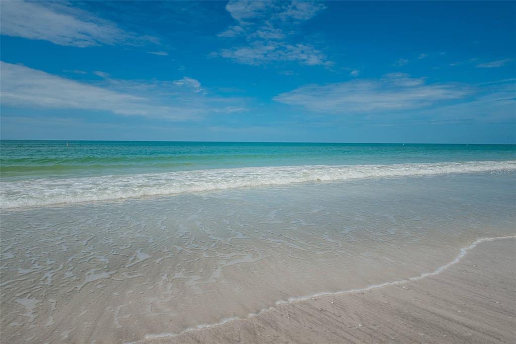 A view of a sandy beach with gentle waves meeting the shoreline under a blue sky — 3500 E MARITANA DRIVE UNIT 3, ST PETE BEACH, FL