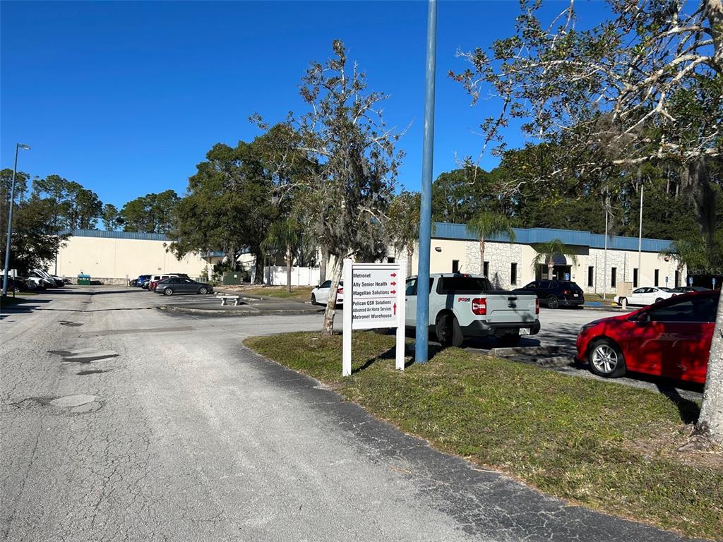 A parking lot in front of a commercial building with a directional sign — 11 COMMERCE BOULEVARD UNIT 1, PALM COAST, FL