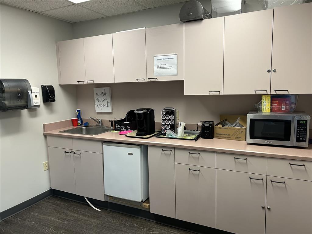 A breakroom features light-colored cabinets, a sink, a microwave, a small refrigerator, and a coffee maker — 11 COMMERCE BOULEVARD UNIT 1, PALM COAST, FL