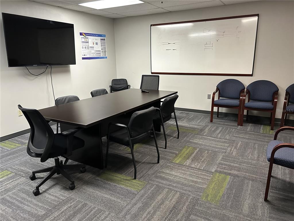 A conference room features a long table, black office chairs, a television, and a whiteboard — 11 COMMERCE BOULEVARD UNIT 1, PALM COAST, FL