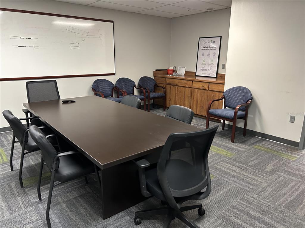 A conference room features a large dark table, surrounding office chairs, a whiteboard, and cabinetry — 11 COMMERCE BOULEVARD UNIT 1, PALM COAST, FL