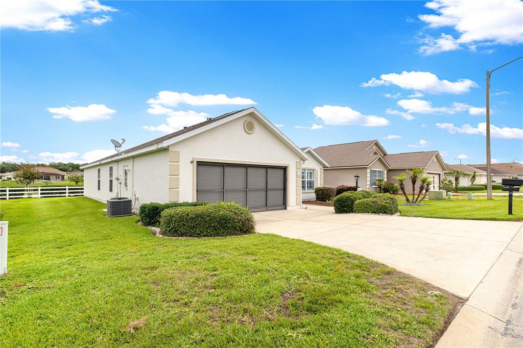 A single-story house with a beige stucco exterior, a two-car garage, and a concrete driveway — 11137 SE 173RD PLACE, SUMMERFIELD, FL