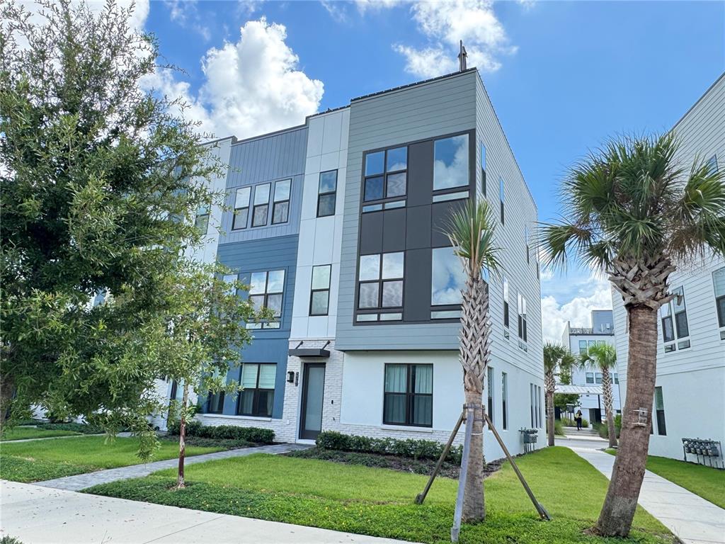 A three-story modern townhouse features blue and white siding with a brick-accented entryway — 2362 ADDALIA ALLEY, ORLANDO, FL