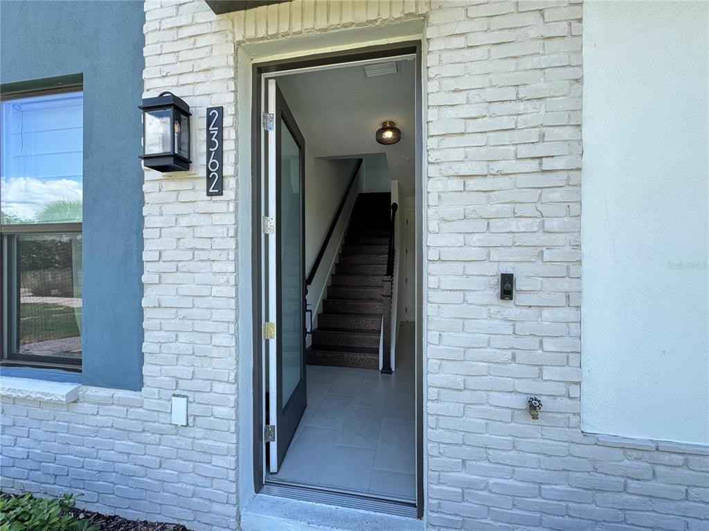 An open front door reveals a tiled entryway and a wooden staircase inside a home — 2362 ADDALIA ALLEY, ORLANDO, FL
