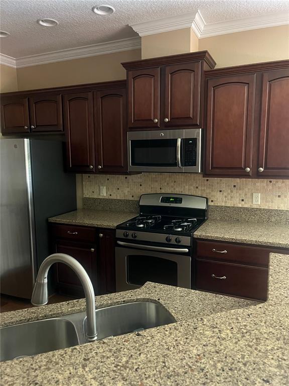 A kitchen features dark wood cabinets, granite countertops, stainless steel appliances, and a tiled backsplash — 1385 ABBOT WAY, DELAND, FL