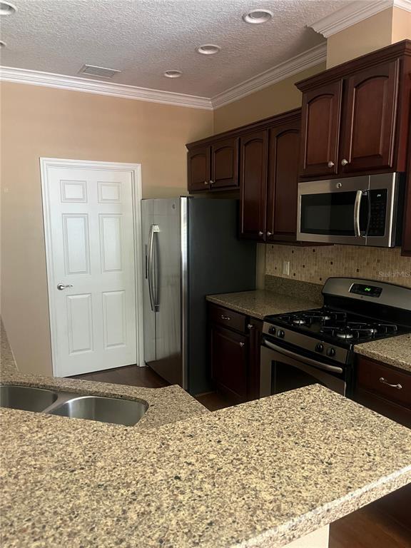 A kitchen features dark wood cabinets, stainless steel appliances, and speckled granite countertops — 1385 ABBOT WAY, DELAND, FL
