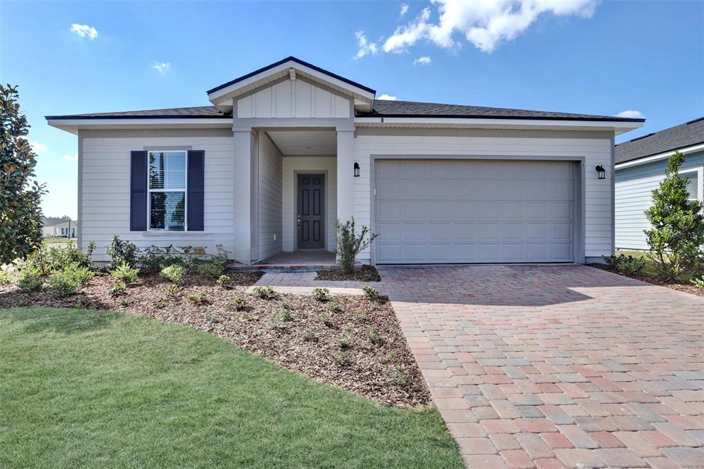 A single-story house with light siding, a gray garage door, and a brick paver driveway — 56 JACKSON BLUE DRIVE, PALM COAST, FL