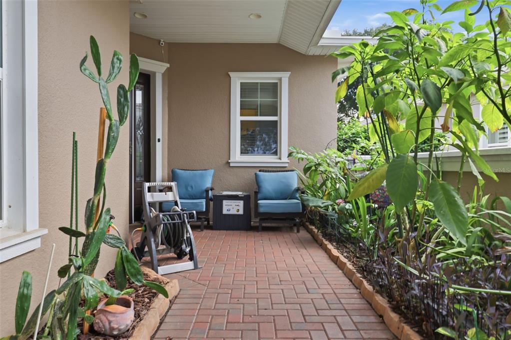 A brick-paved patio features two blue chairs, a small table, and surrounding garden plants — 273 SILVER MAPLE ROAD, GROVELAND, FL