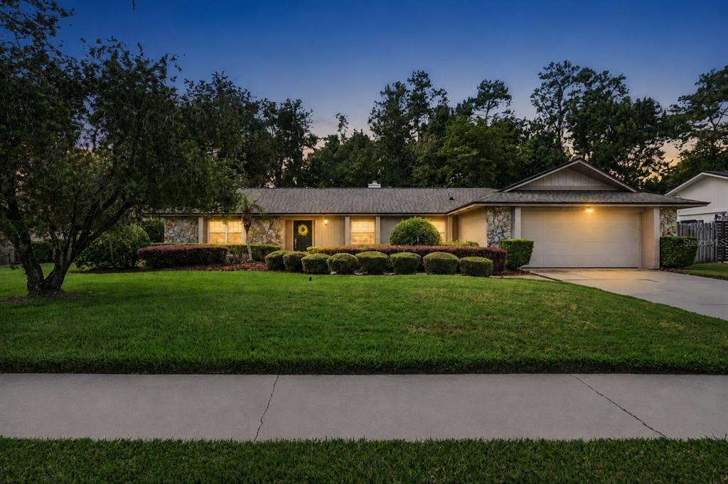 A single-story house with a stone facade, a two-car garage, and a manicured front lawn — 734 RIVERBEND BOULEVARD, LONGWOOD, FL
