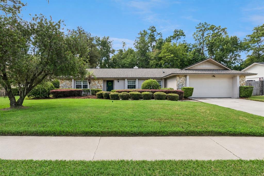 A single-story house with a stone facade, a two-car garage, and a manicured front lawn — 734 RIVERBEND BOULEVARD, LONGWOOD, FL