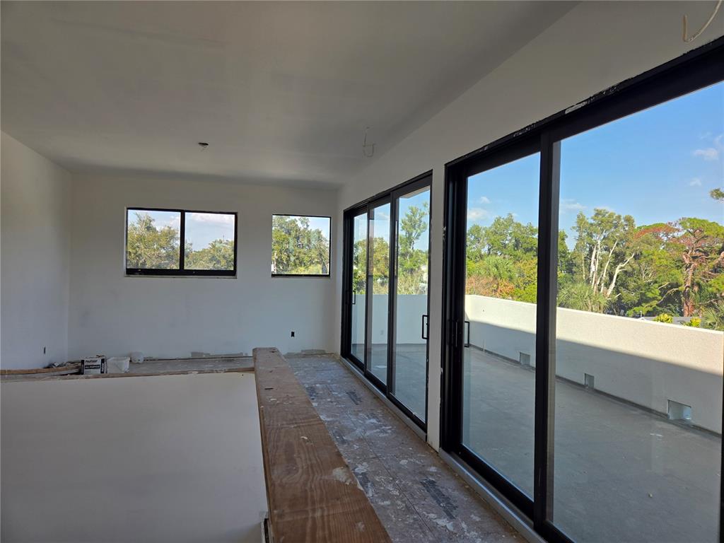 An unfinished room features large sliding glass doors opening onto a balcony with outdoor views — 1755 8TH STREET UNIT West, SARASOTA, FL