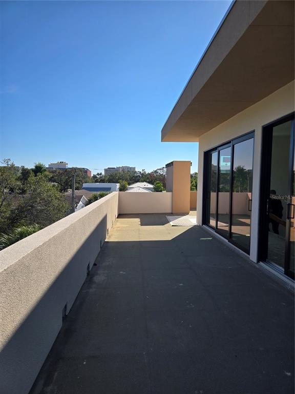 A spacious outdoor balcony features a concrete floor, stucco walls, and large sliding glass doors — 1755 8TH STREET UNIT West, SARASOTA, FL
