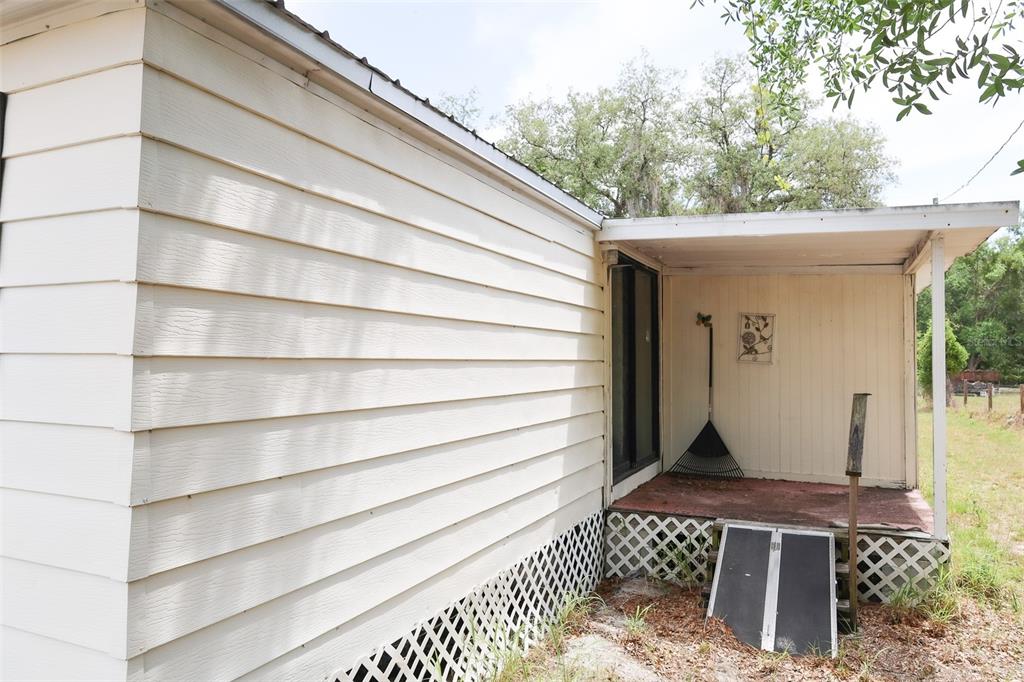 The exterior of a house features light-colored horizontal siding, a covered porch, and lattice skirting — 220 KING ROAD, WINTER HAVEN, FL