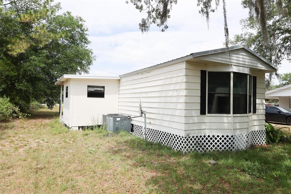The exterior of a white mobile home features horizontal siding, a bay window, and lattice skirting — 220 KING ROAD, WINTER HAVEN, FL