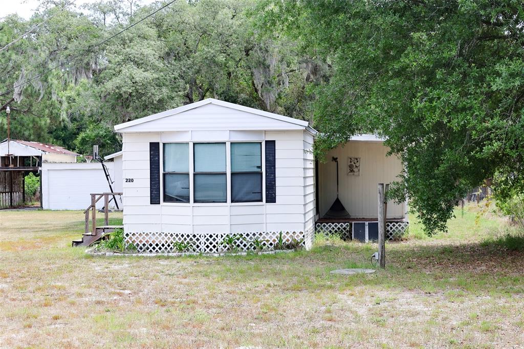 A white mobile home with a front porch and lattice skirting sits on a grassy lot — 220 KING ROAD, WINTER HAVEN, FL