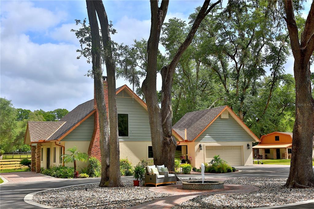 A two-story house with light green siding, a brick chimney, and a front yard fountain — 10925 SW 16TH AVENUE, OCALA, FL