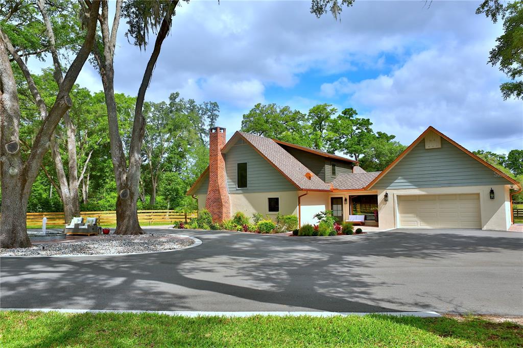 A two-story house with a brick chimney, light-colored siding, and an attached garage — 10925 SW 16TH AVENUE, OCALA, FL