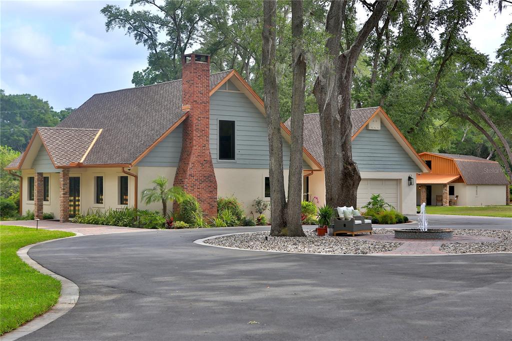 A two-story house with a brick chimney, blue siding, and a circular driveway with a fountain — 10925 SW 16TH AVENUE, OCALA, FL