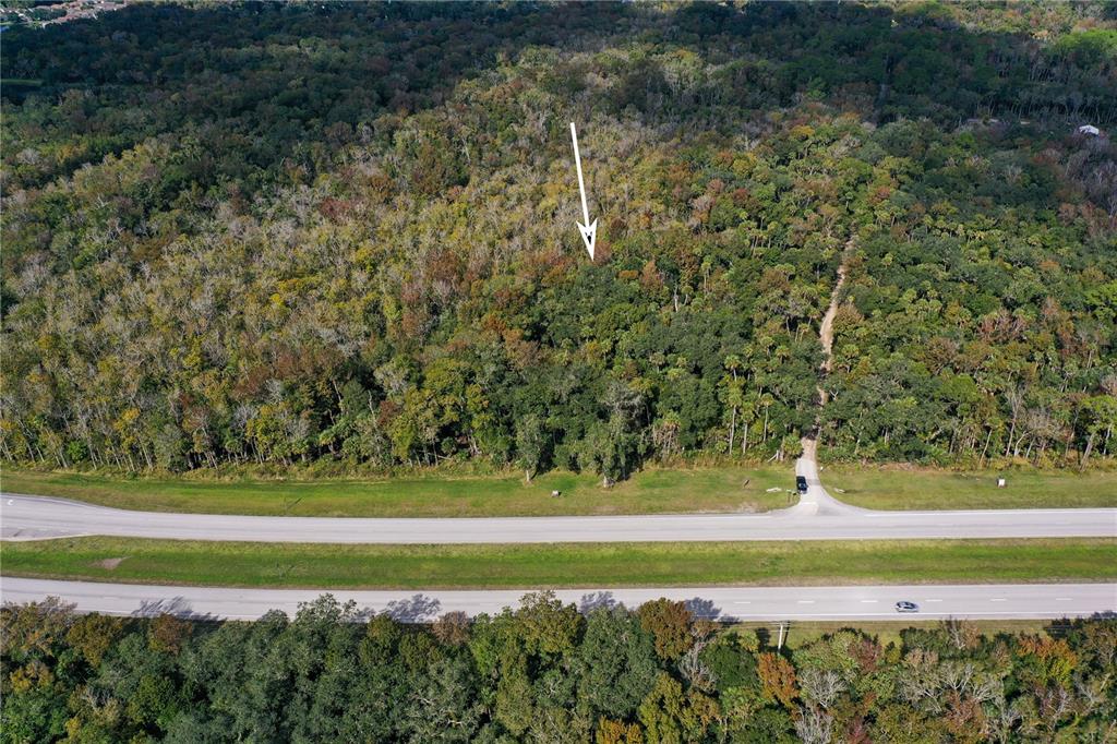 An aerial view shows a wooded lot adjacent to a multi-lane highway — W INDIAN RIVER BOULEVARD, EDGEWATER, FL