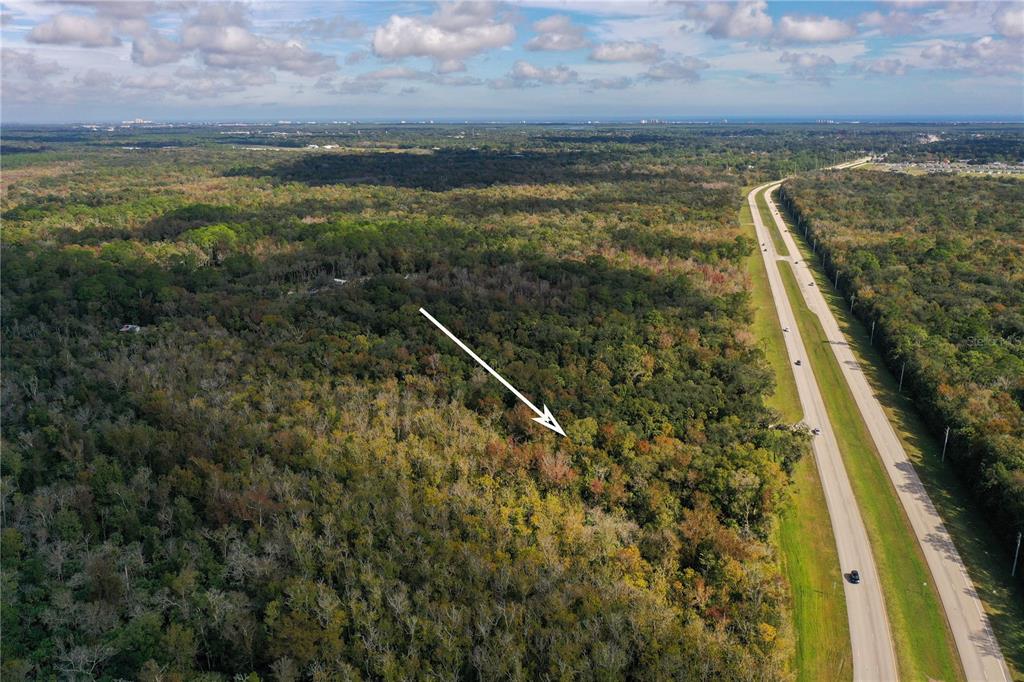 An aerial view shows a large, wooded lot adjacent to a divided highway — W INDIAN RIVER BOULEVARD, EDGEWATER, FL