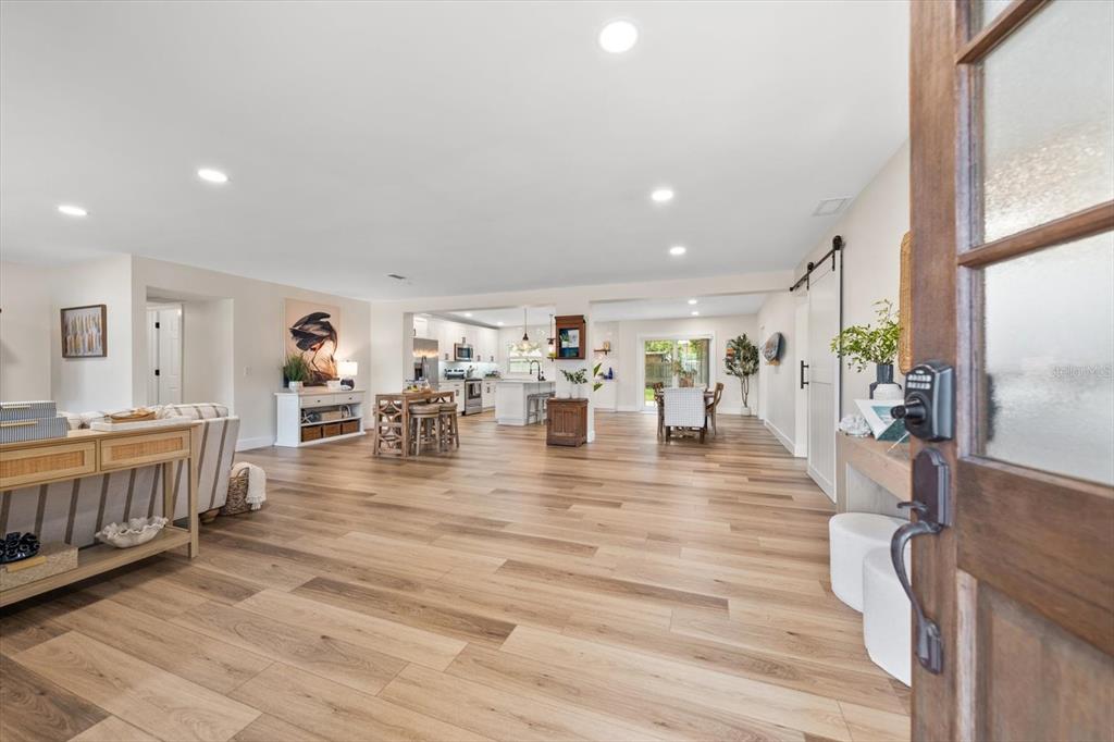 A view from a doorway into an open-concept living area with light wood-look flooring — 1736 GOLF VIEW DRIVE, BELLEAIR, FL
