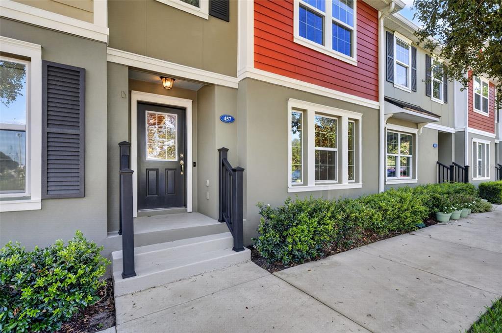 The exterior of a multi-story townhouse features a dark front door and red siding — 457 GEE HAMMOCK LANE, WINTER SPRINGS, FL