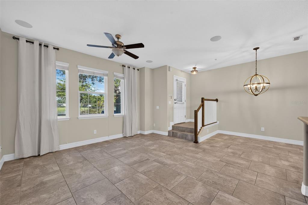 A living area with tile flooring, a ceiling fan, and a staircase leading to a door — 457 GEE HAMMOCK LANE, WINTER SPRINGS, FL