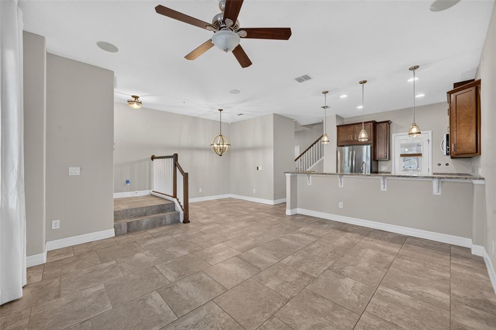 An open-concept living area features tile flooring, a kitchen island, and a raised dining space — 457 GEE HAMMOCK LANE, WINTER SPRINGS, FL