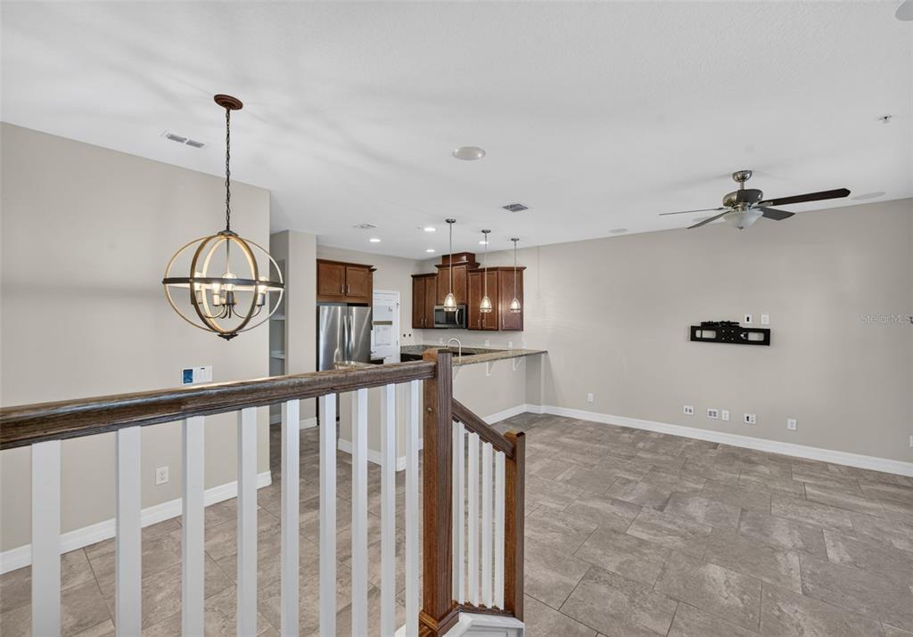 An open-concept kitchen and living area features tile flooring, wood cabinetry, and a staircase railing — 457 GEE HAMMOCK LANE, WINTER SPRINGS, FL